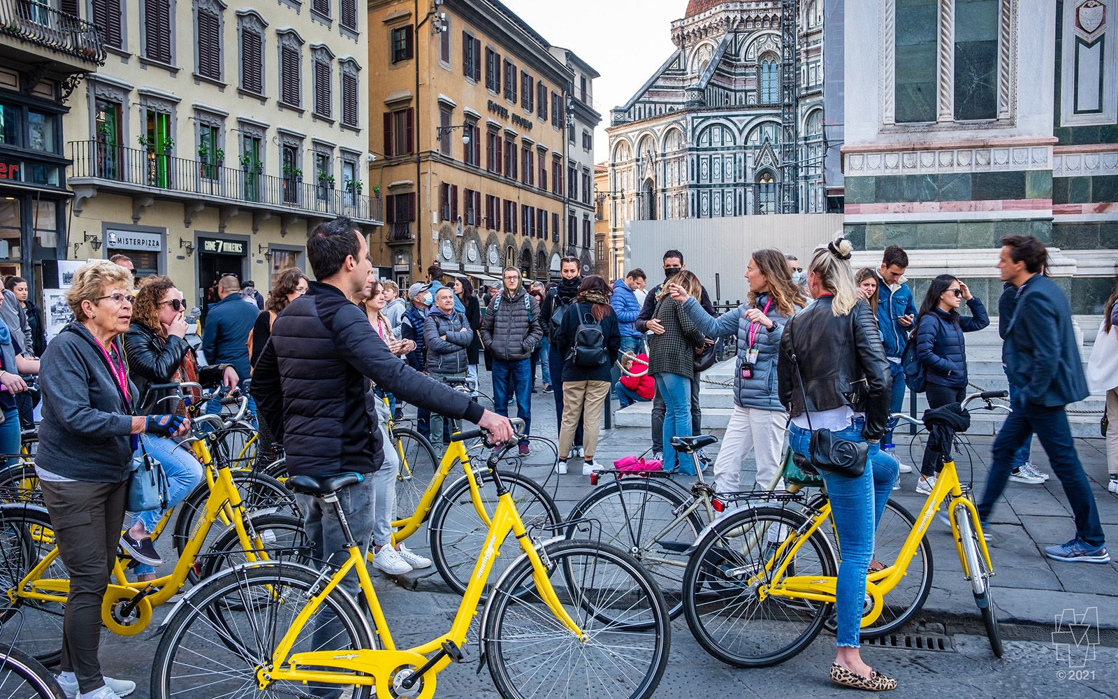 A tour guide leads visitor on a bike tour of Firenze, Italia, with its Duomo in the background.