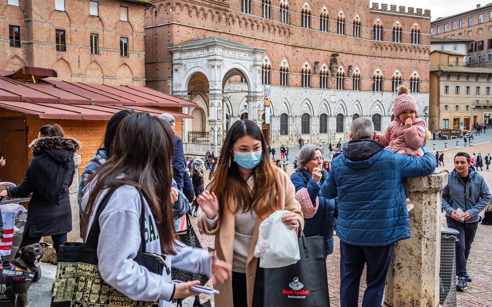 Visitors at the Campo with Palazzo Publico in the background in Siena, Italia.